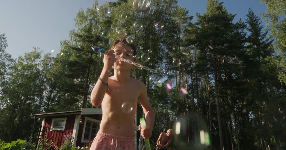 Boy playing with soap bubbles and an elderly person in the background