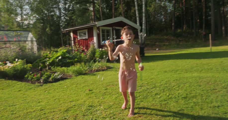 Boy in a garden blowing and making soap bubbles