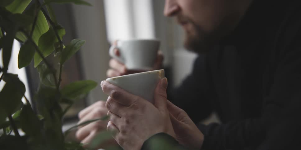 A woman holds a cup of coffee in her hands as a man next to her drinks from a coffee cup