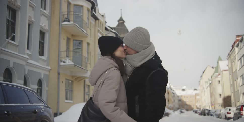 Couple walking together through a city covered in snow and kissing