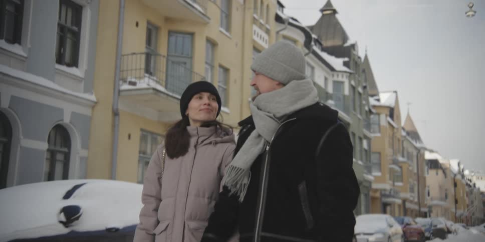 Couple of a man and a woman walking through a residential neighborhood covered in snow