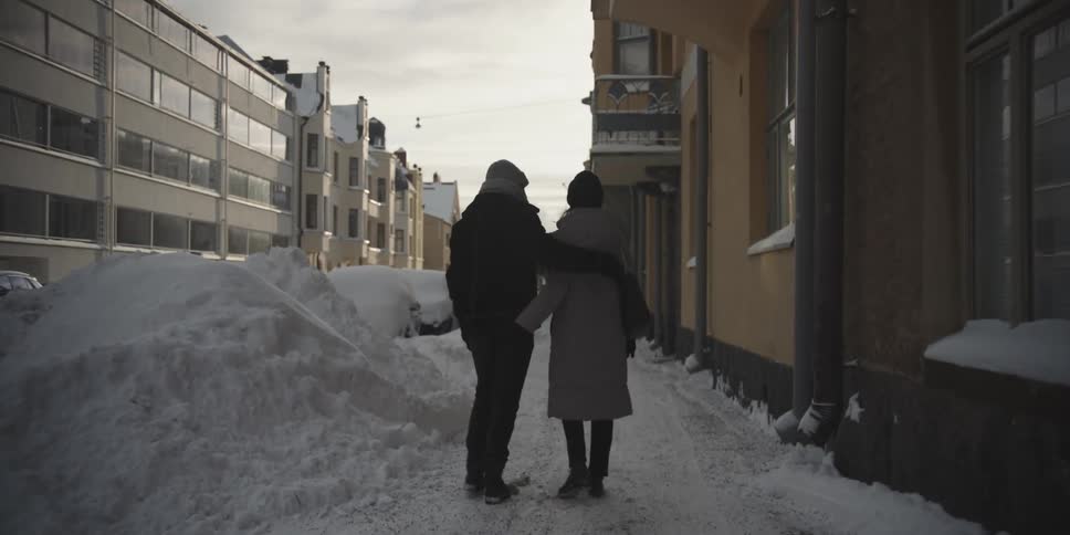 Man and woman holding hands and walking through a snow covered city