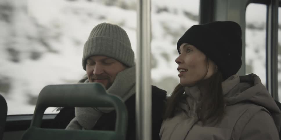 Man and woman happily chatting while sitting on a moving bus