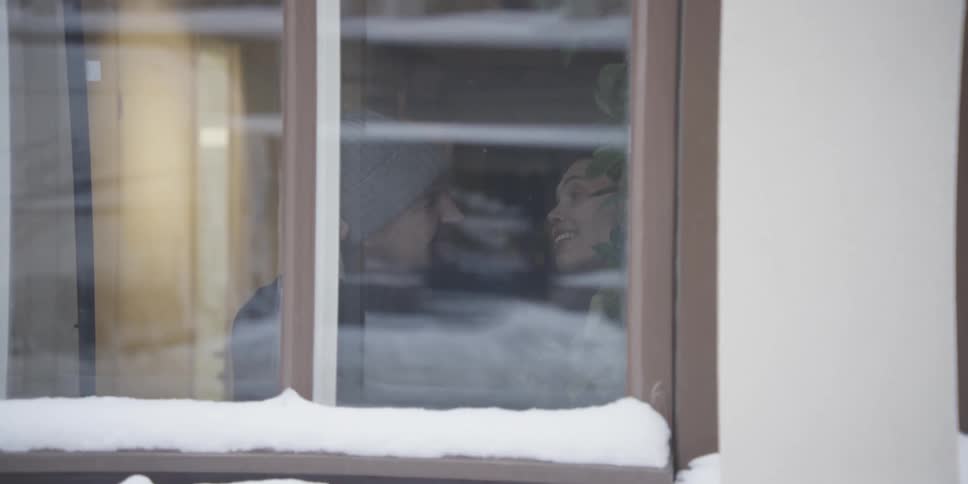 Man and woman inside a establishment drinking coffee seen from the window on a winter day
