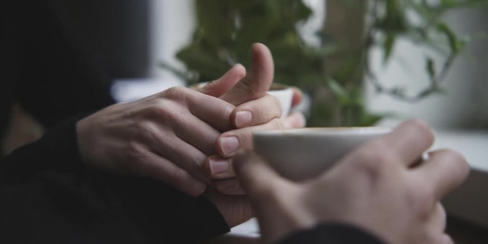 Two people holding hands holding cups of coffee