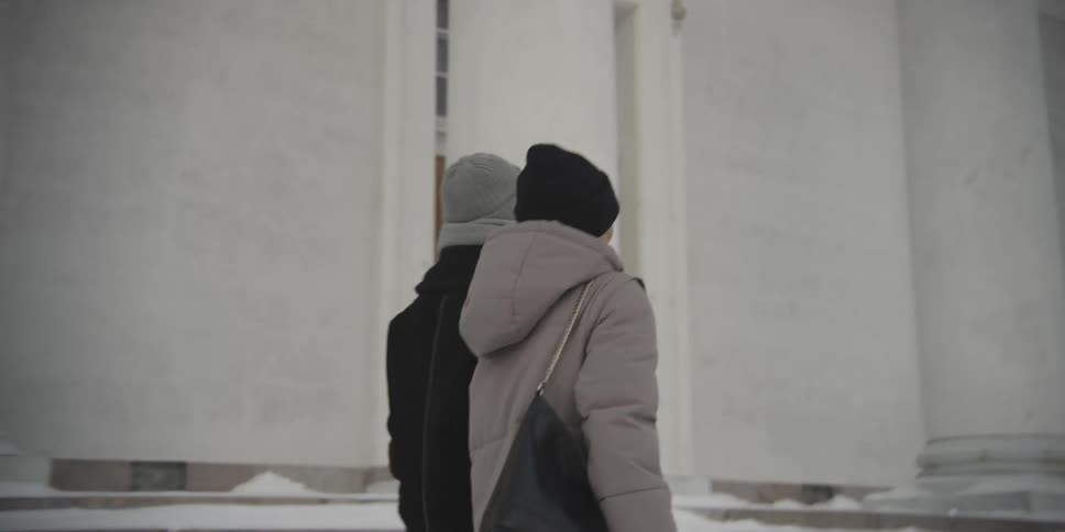 Woman and man holding hands walking through a room next to a classic building