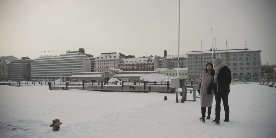 A couple holds hands while walking through the snow in a city