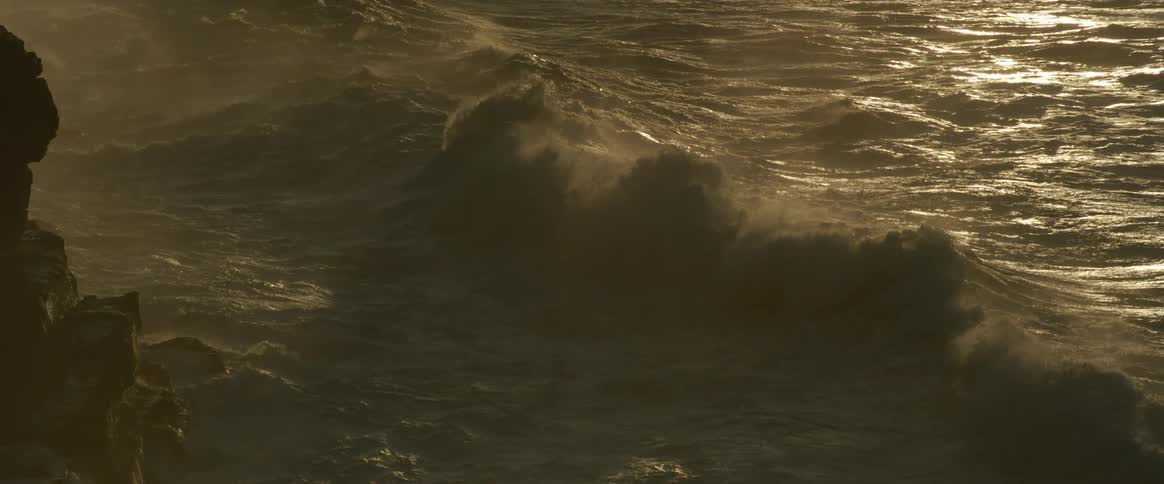 Strong ocean wave approaching rocky shore