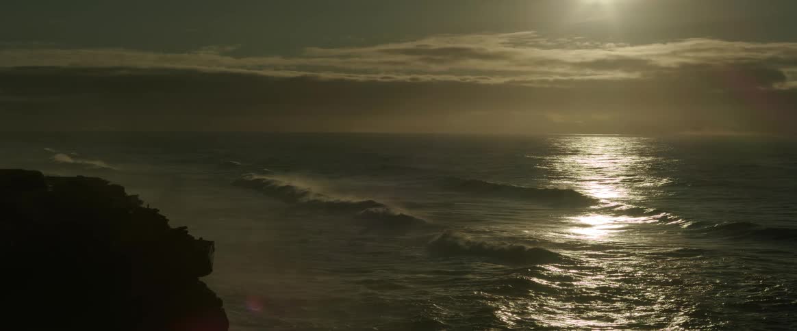 Ocean waves roll into a rocky coastline at sunset