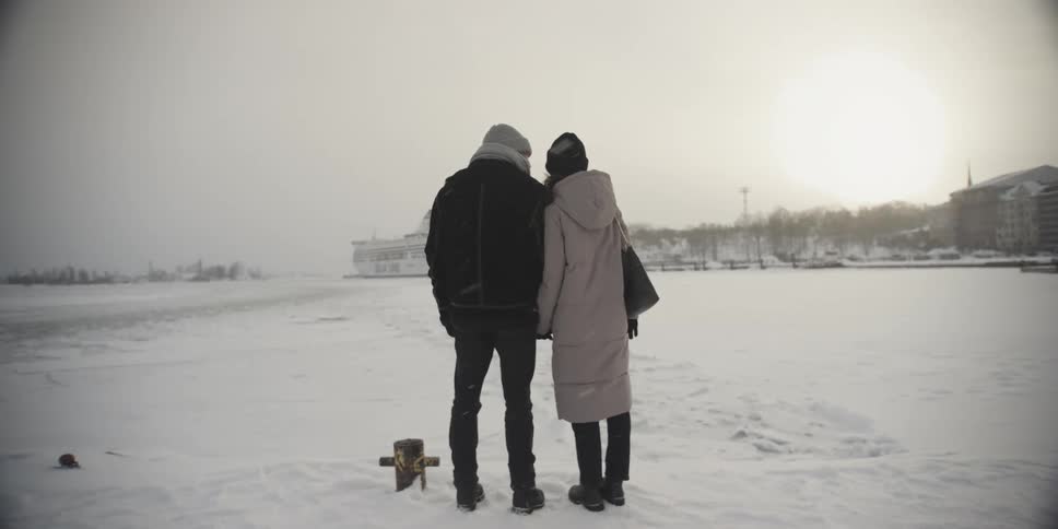 Back view of a man and a woman holding hands in a snowcovered environment in a city square