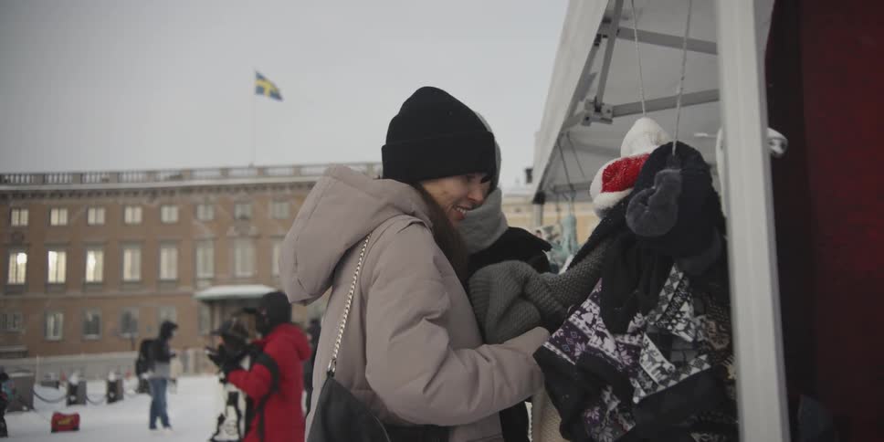 A couple in winter clothing shopping at a stall in a public plaza during winter
