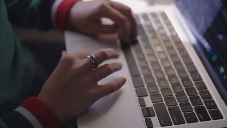 A person types on a laptop while sitting on an airplane