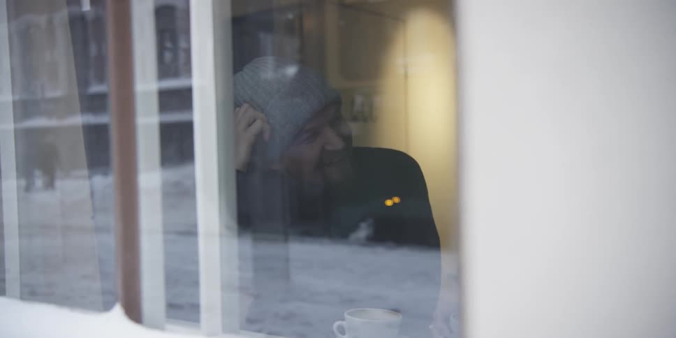Man drinking coffee and talking to a woman while sitting inside a restaurant