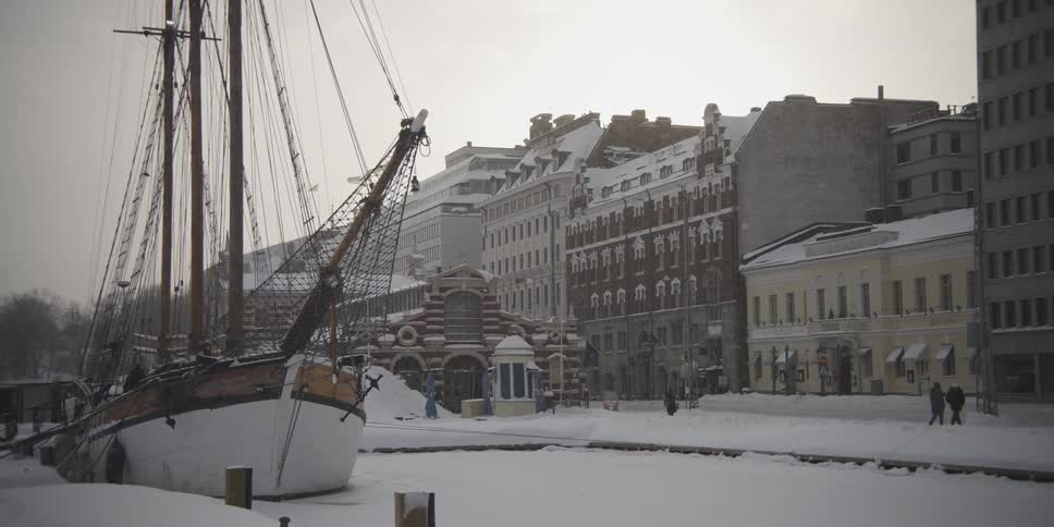 People walk past the buildings as it snows