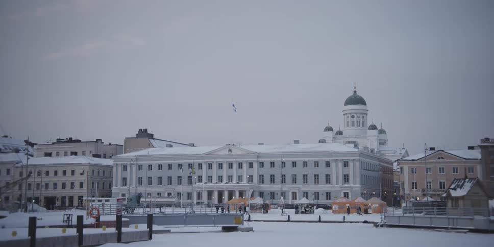 Classical buildings facing a square with people on a snowy day