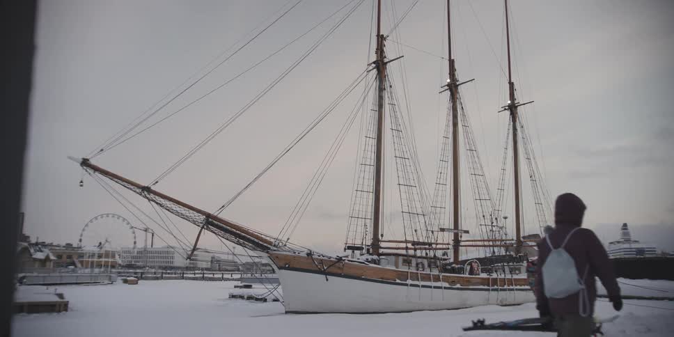 People walking next to a sailboat attacked on a snow covered dock