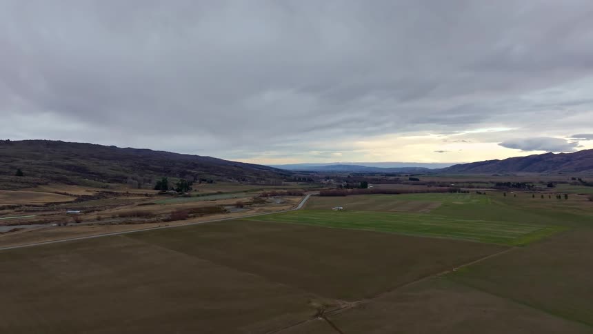 Aerial panorama of a vast farmed countryside with mountains on the horizon