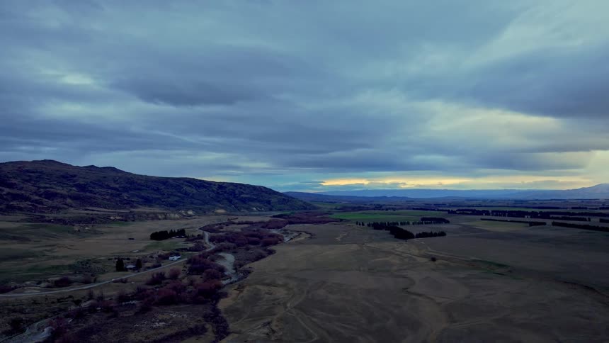 Aerial landscape of a vast field with mountains on the horizon at dusk
