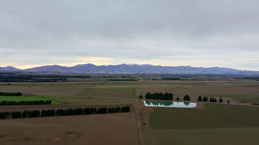 Aerial landscape of fields with mountains on the horizon on a cloudy morning