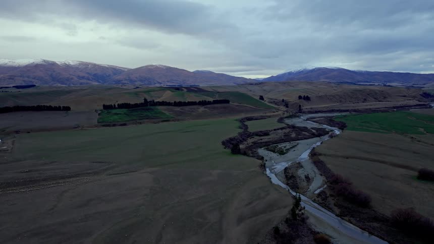 Aerial panorama of a winding river surrounded by plateaus and mountains on a cloudy day