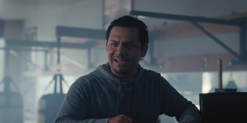 Portrait of a coach talking and motioning with his arms while standing in a boxing gym