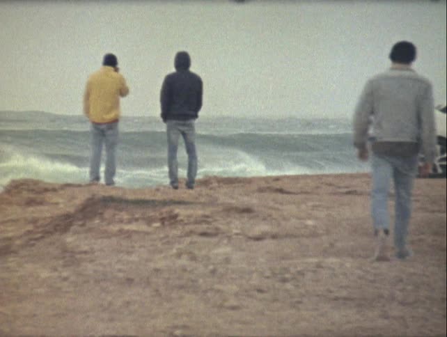 A man walks over to two people on the beach