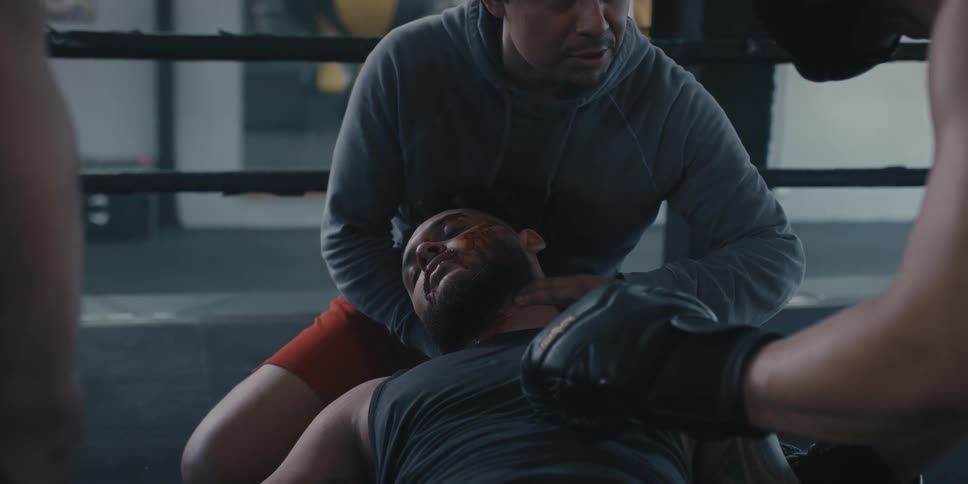 Man in a boxing ring checking if a person is alive