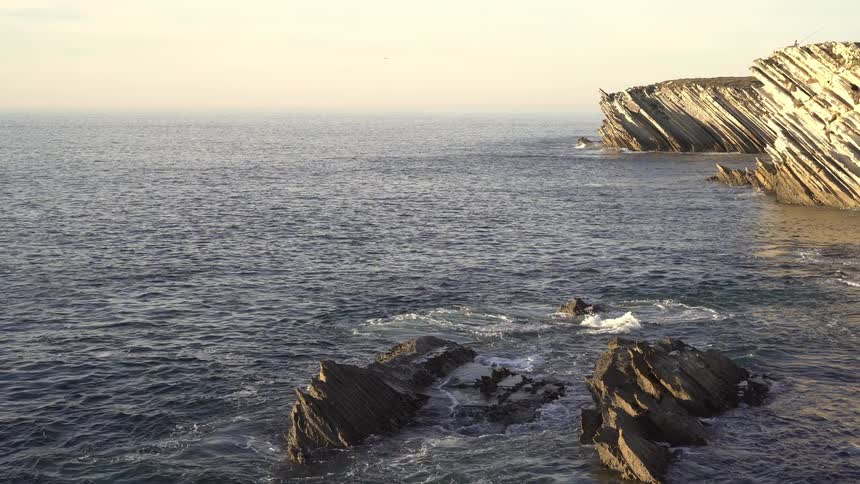 Calm ocean with a rocky coastline in the background on a morning