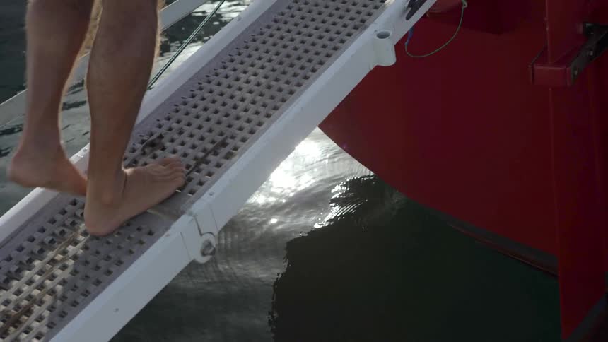 Closeup of a persons bare feet climbing on a white metal ramp with holes