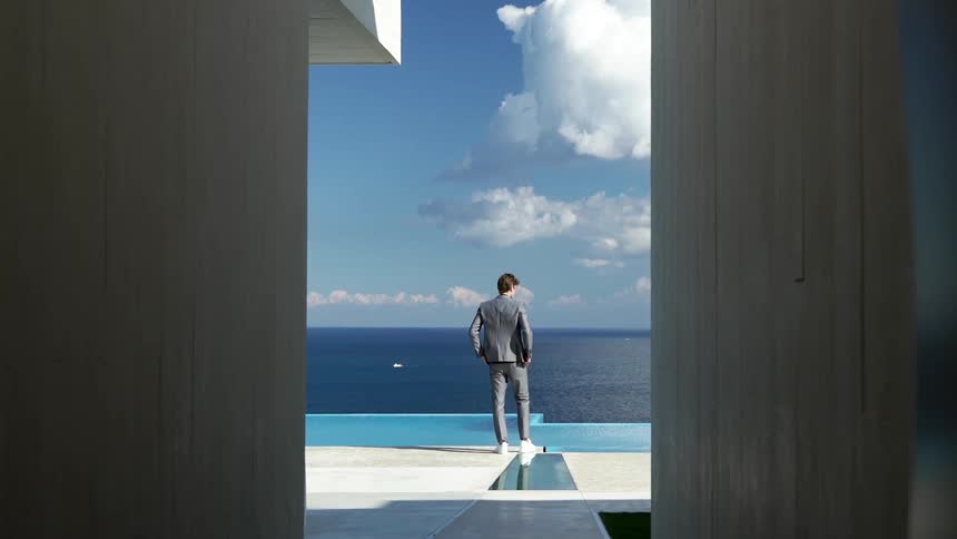 Man in suit walking towards a beachfront swimming pool