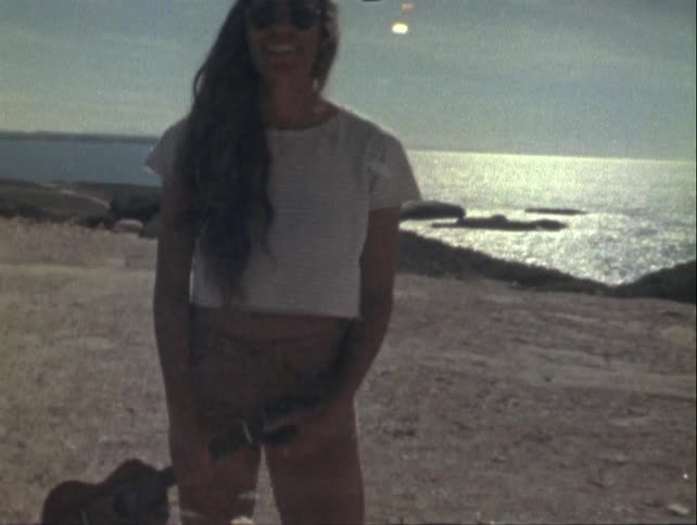 Smiling woman holding a small violin at the seaside