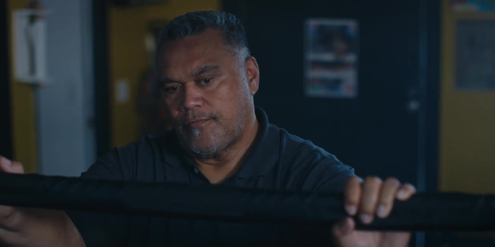 Closeup of a boxing coach standing next to a boxing ring watching a fight inside the ring