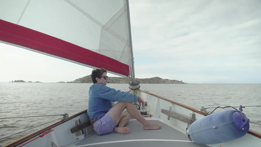 Man sitting on the edge of a sailing boat moving through the sea