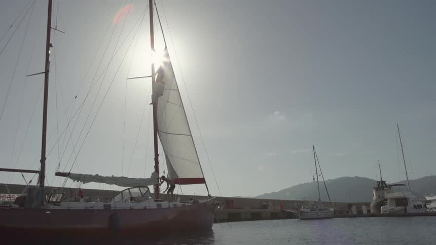 Person on top of a sailboat moored at a dock