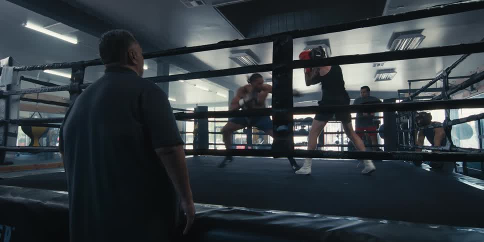 Two men fighting in a boxing ring and people watching outside