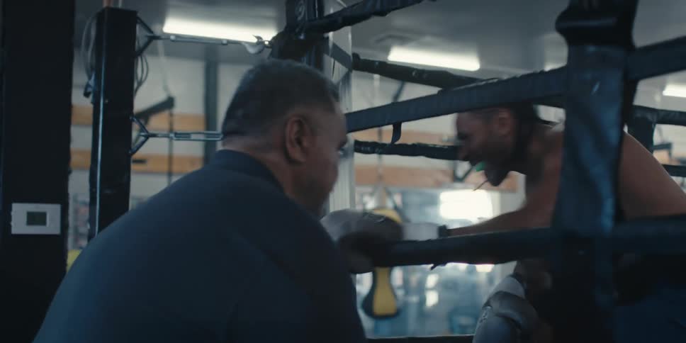 Trainer talking to his boxer who is tired inside the ring