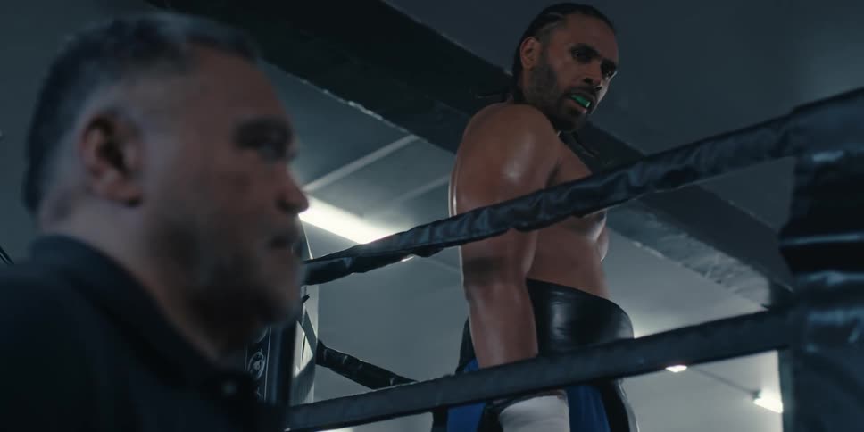 Boxer standing in a boxing ring turns to look at his coach