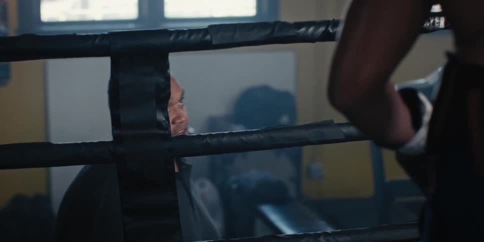 Man talking to his student who is inside a boxing ring