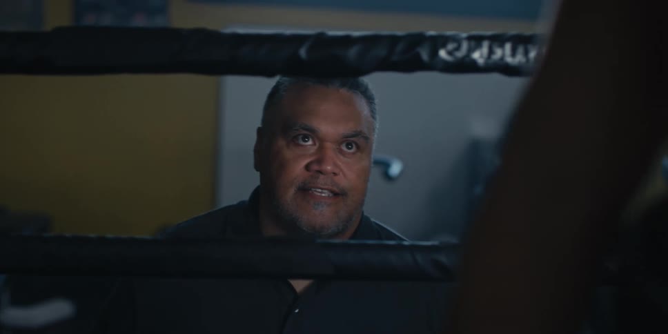 A coach is talking to a boxer in the ring
