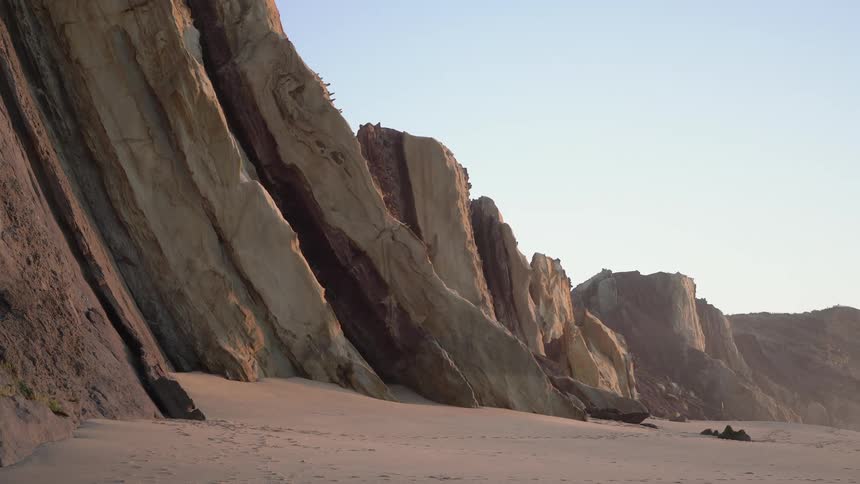 Tall stone cliffs line the beach