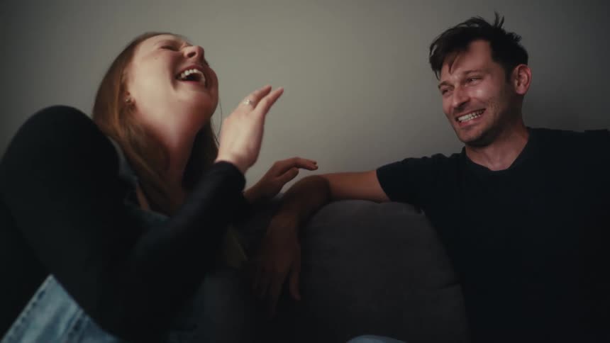 A young happy couple talking and laughing on the couch at home