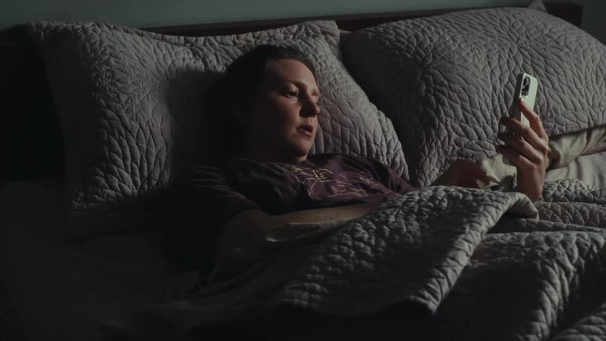 Woman lying in bed interacting with an iphone