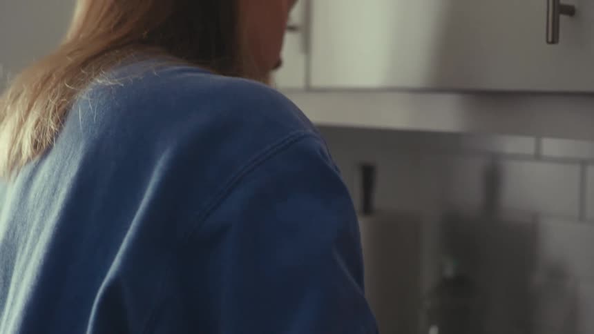 Woman in the kitchen washing a glass cup