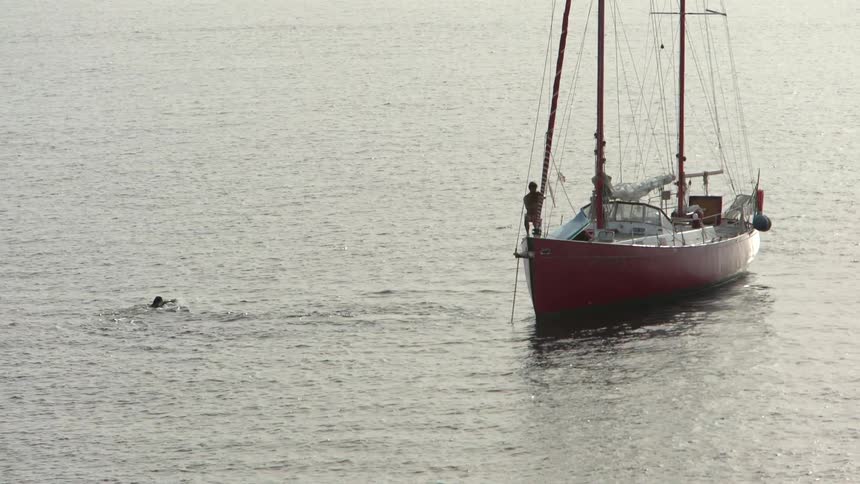 A man and woman dive off the boat into the water