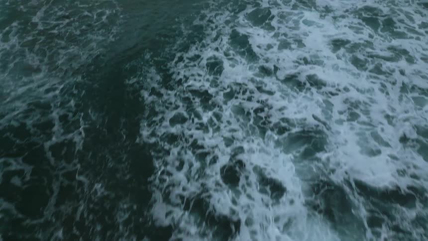 Flying over ocean and camera pans up to look at the horizon