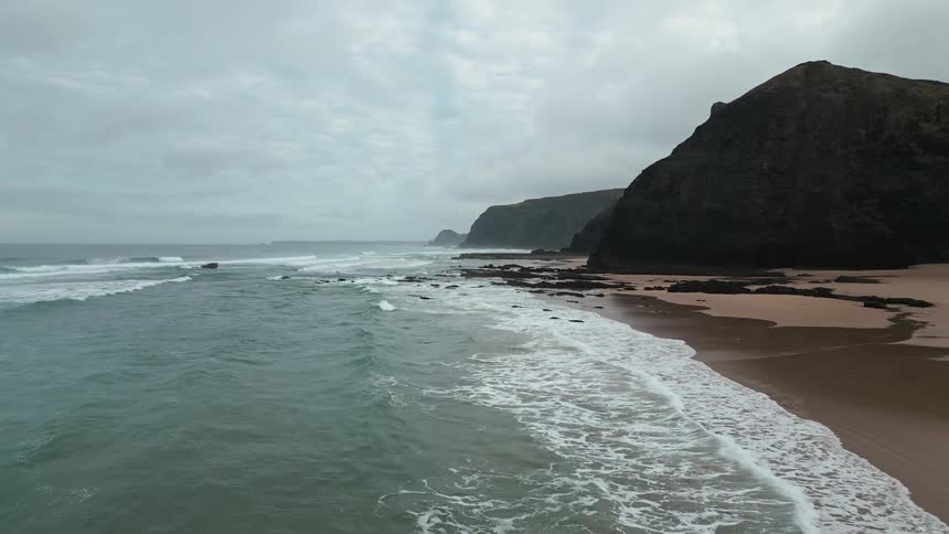 Long beach on the edge of the rocky coast view during a cloudy day