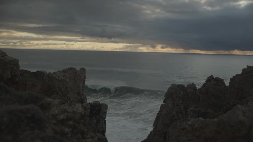 Natural landscape on a cloudy day with sea waves crashing onto the rocky shore