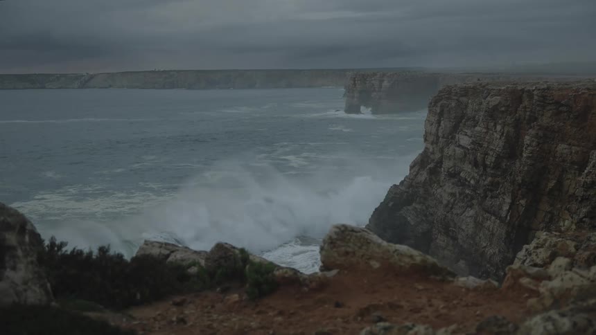 Landscape of strong waves crashing on rocky shore on a cloudy day