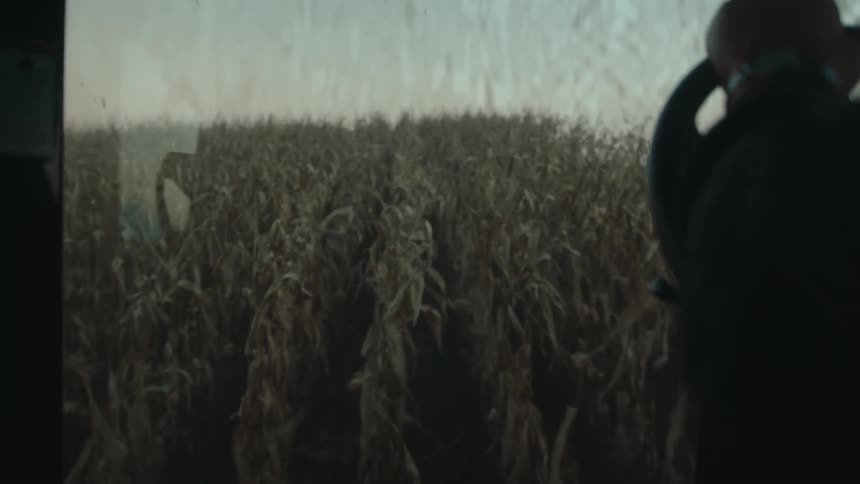 Hand on the steering wheel controlling an agricultural machine and carrying out a harvest