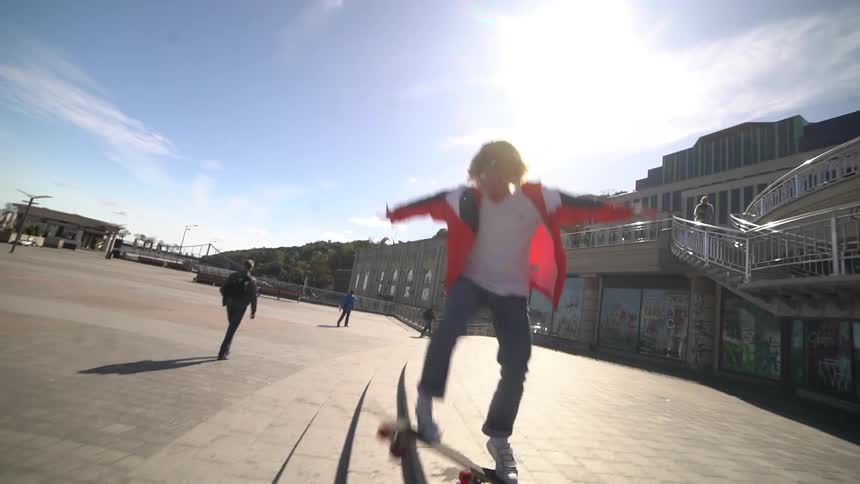 A young man performs a skateboarding trick over the stairs of an open public space